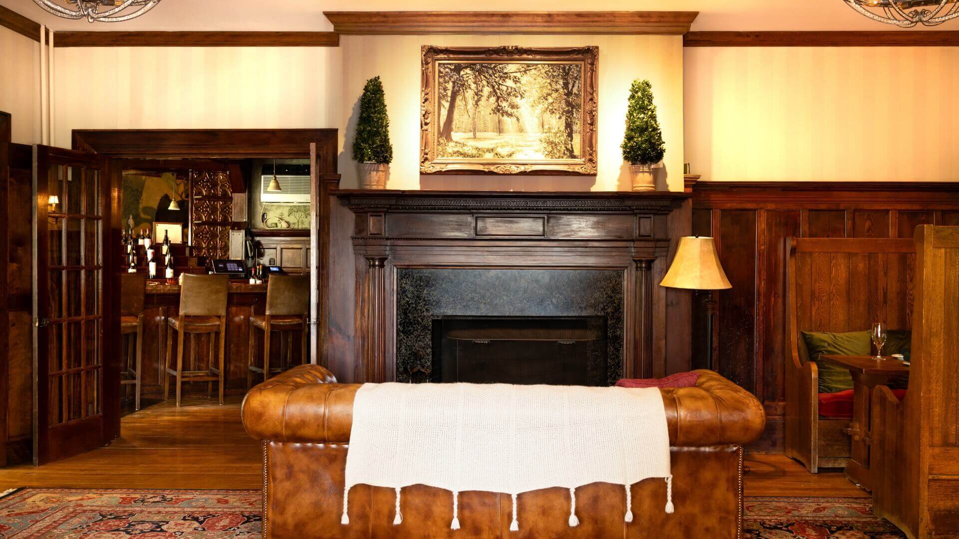 Cozy living room featuring a leather couch, a decorative fireplace, and a bar area in the background.