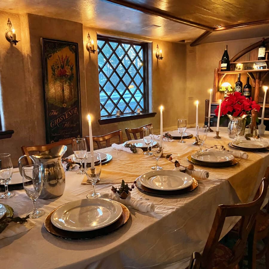 A beautifully set dining table with candles and festive decorations, illuminated by warm lighting.